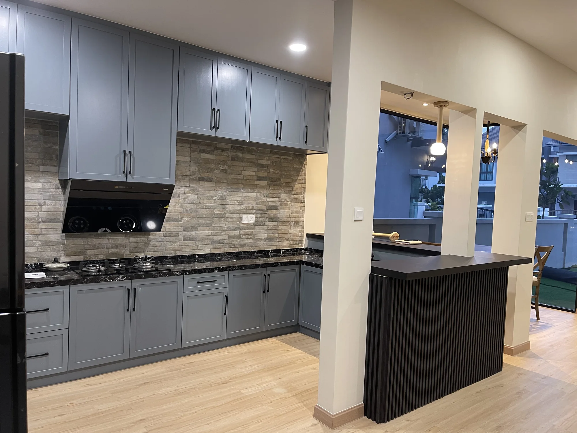 Completed grey kitchen cabinetry and black fluted bar counter